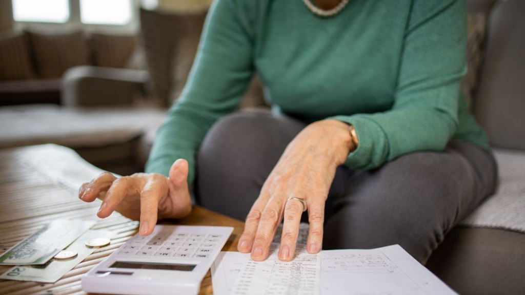 Senior woman using calculator while going through bills and home finances
