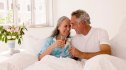A happy midlife couple who have a healthy sex life drinking champagne together in bed