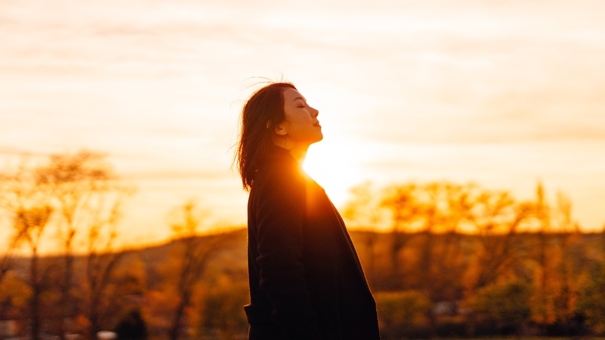 A woman smiling while looking toward a sunrise after learning how to manage Effexor side effects