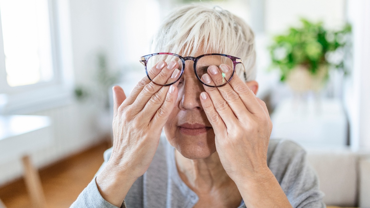 A woman rubs her eyes due to eye pain