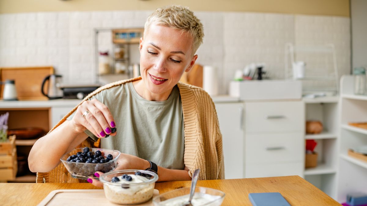 A woman eating blueberries, a healthy food to add to your diet while taking metformin