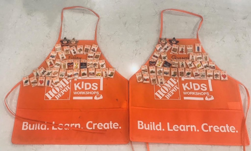 Orange aprons from Home Depot's Kid Workshops filled with project pins.