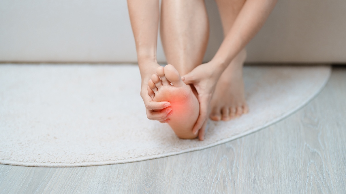 woman massages the ball of her foot, where a plantar wart is located