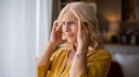 A woman rubbing her temples, wondering if her memory loss is a sign of dementia