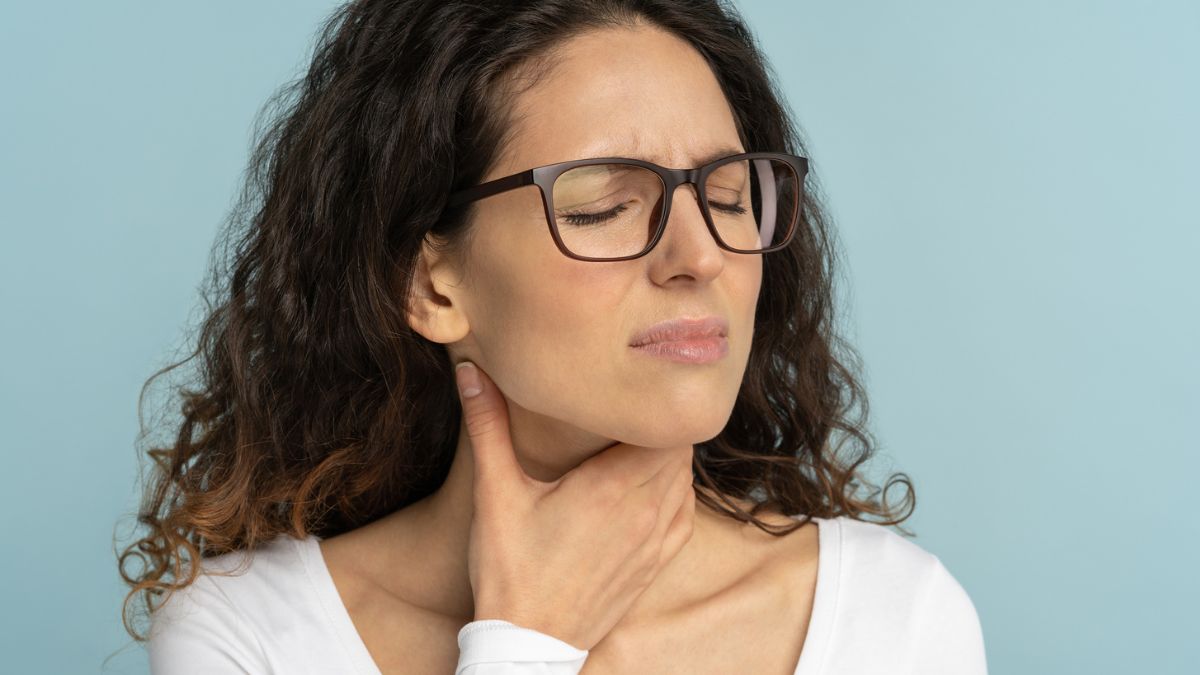 A woman holding her throat with her hand due to silent reflux