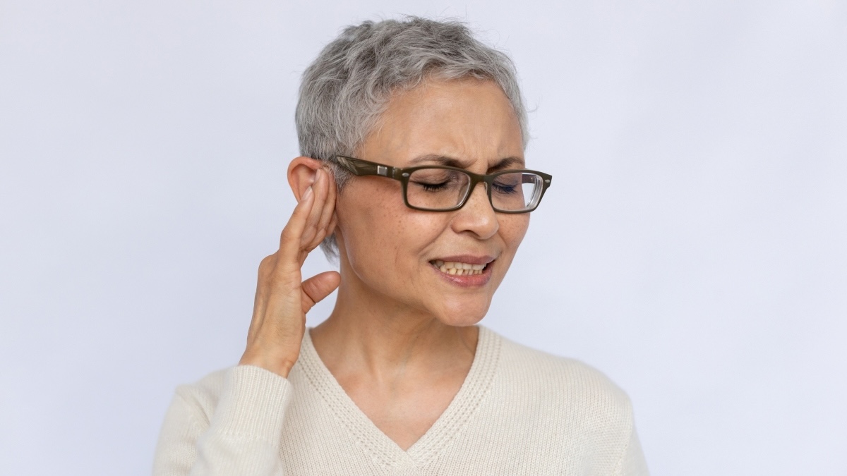 A woman holding her ear due to tinnitus