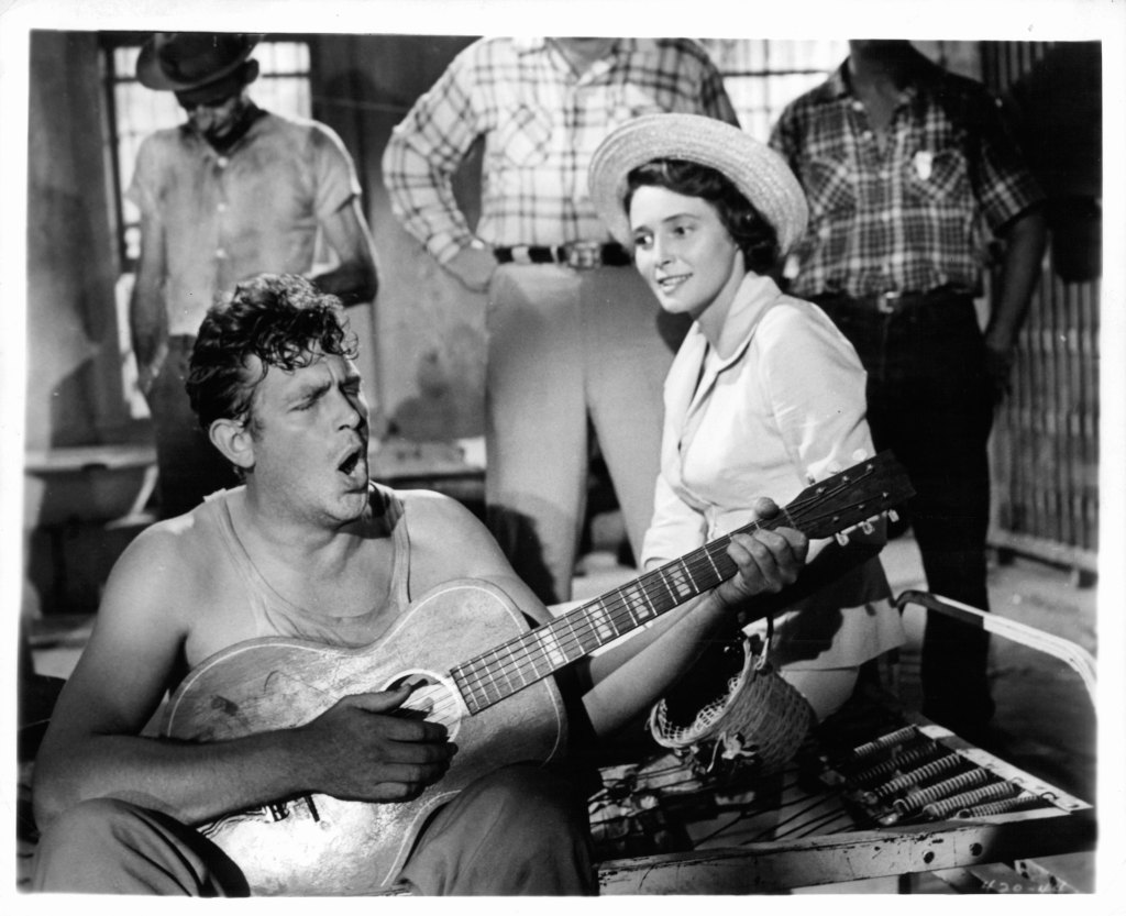 Andy Griffith playing guitar as Patricia Neal watches in a scene from the film 'A Face In The Crowd', 1957. 