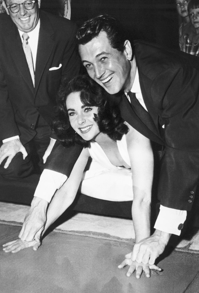 Elizabeth Taylor gets an assist from actor Rock Hudson, as she plants her hands in cement in the lobby of Grauman's Chinese Theater here Sept. 26th, in a ceremony held before the premiere of new film 'Giant' (1956)