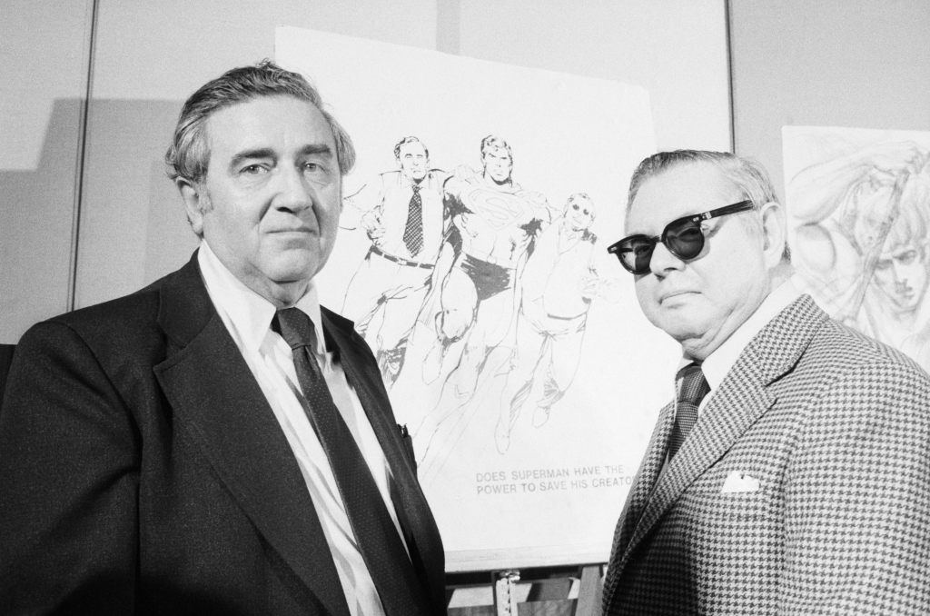 Superman creators Jerry Siegel and Joe Shuster pose in front of sketches of their creation. 