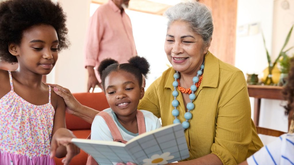Smiling grandmother reading book to grandchildren