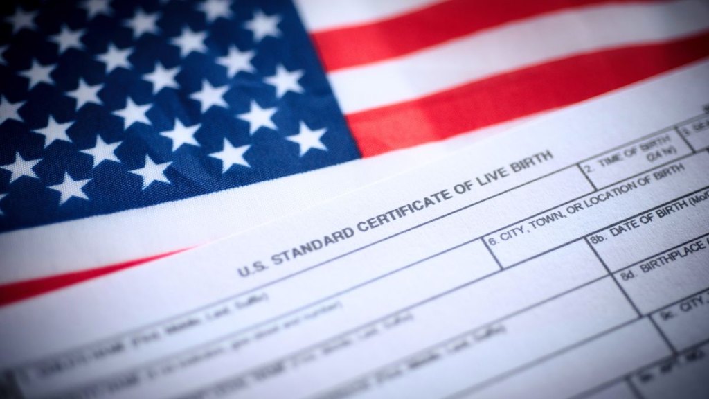US standard certificate of live birth application form next to flag of USA. Birthright citizenship concept