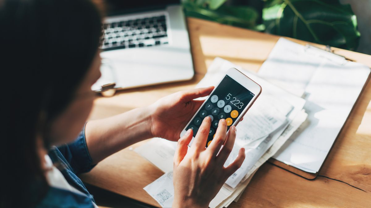 Woman accountant use calculator and computer with holding pen on