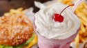 A strawberry milkshake with whipped cream and cherry