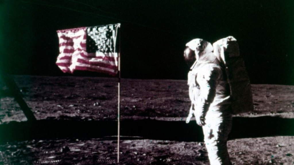 Buzz Aldrin stands next to the American flag on the surface of the moon