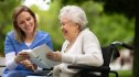 assisted living facility worker reads to an older resident and they both smile