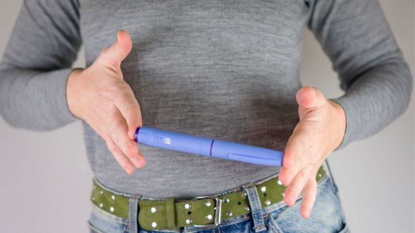 Close-up of woman holding blue GLP-1 pen, which may not work for everyone