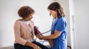 Woman getting her blood pressure checked by doctor to determine her hypertension stage