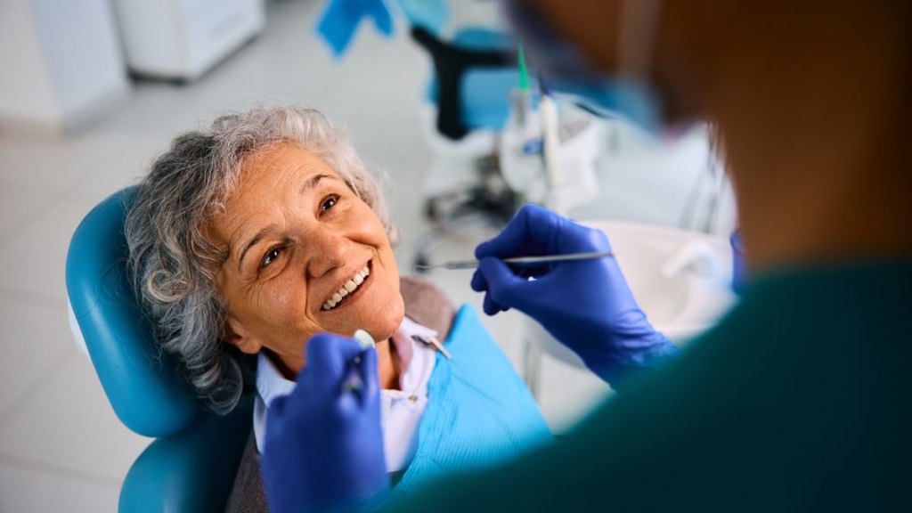 Happy senior woman having her teeth checked by dentist at dental clinic