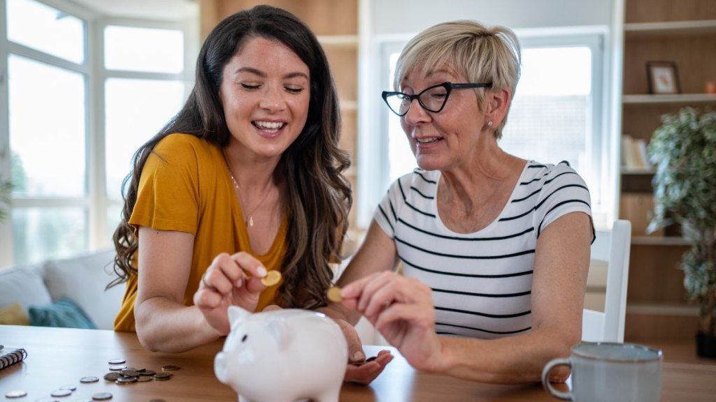 Mother and daughter saving coins in piggy bank