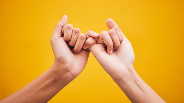 People holding pinkies for pinky time, which is supposed to help ward off cognitive decline