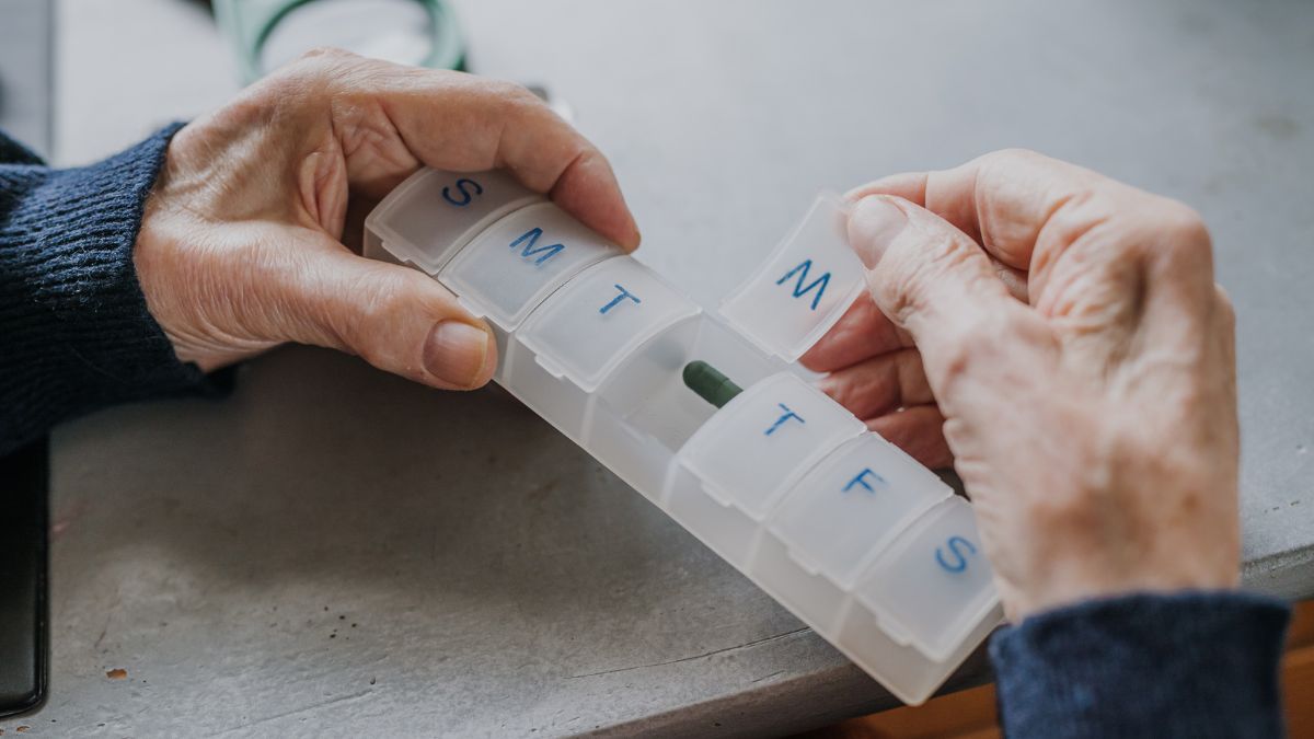 Senior arranges medicines for each day of week
