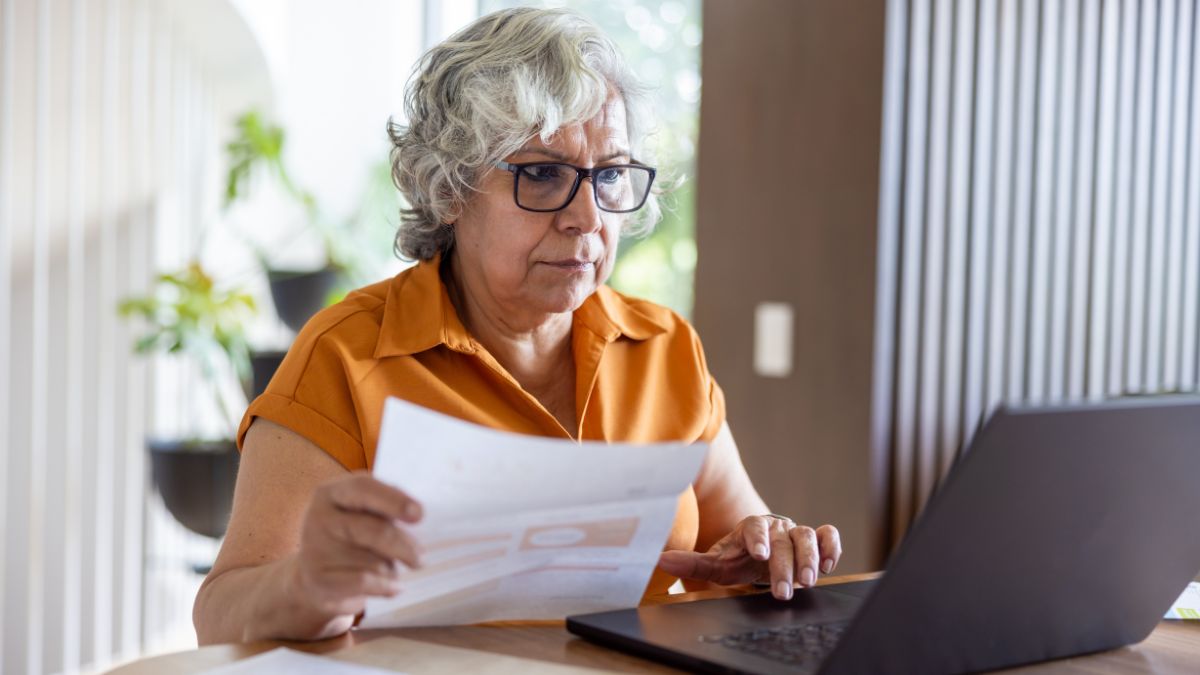 Senior woman at home paying bills online using her laptop