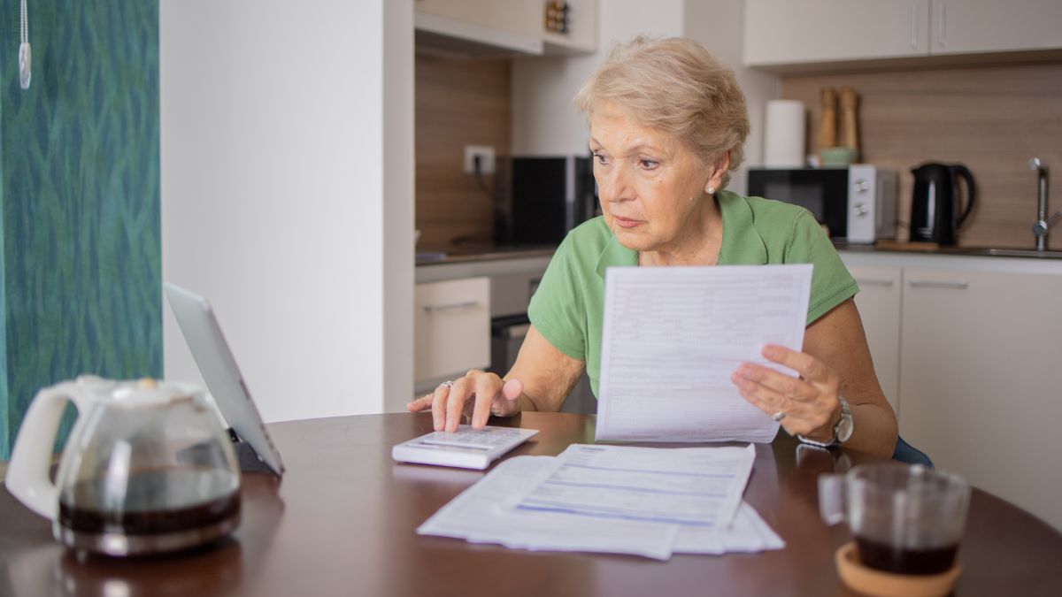 Senior woman using calculator while going through bills and home finances
