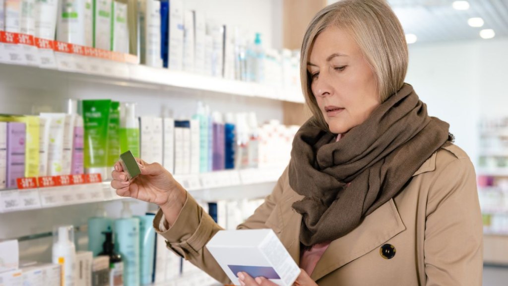 Sick caucasian mature woman choosing pills in a drug store