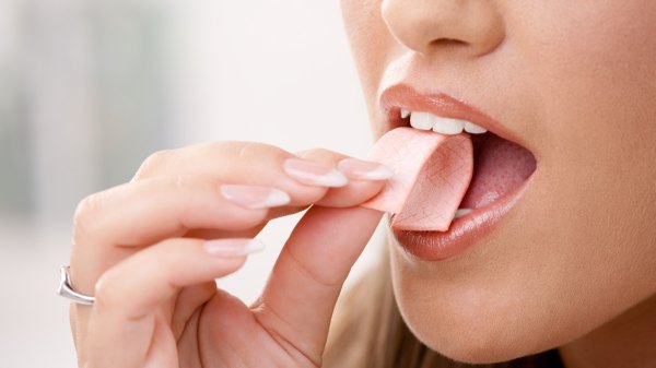 Close-up of a woman chewing a piece of gum to stop sugar cravings
