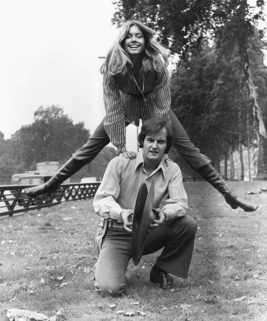 Singer Olivia Newton John leap-frogging over the shoulders of drummer Chris Slade, both members of the band 'Tomorrow', at Park Lane, London, August 25th 1970. 