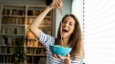 A woman joyfully eats a bowl of noodles without the stress and shame associated with compulsive eating