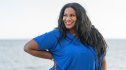 A woman in a blue top smiling after learning how to reduce her cholesterol in 7 days