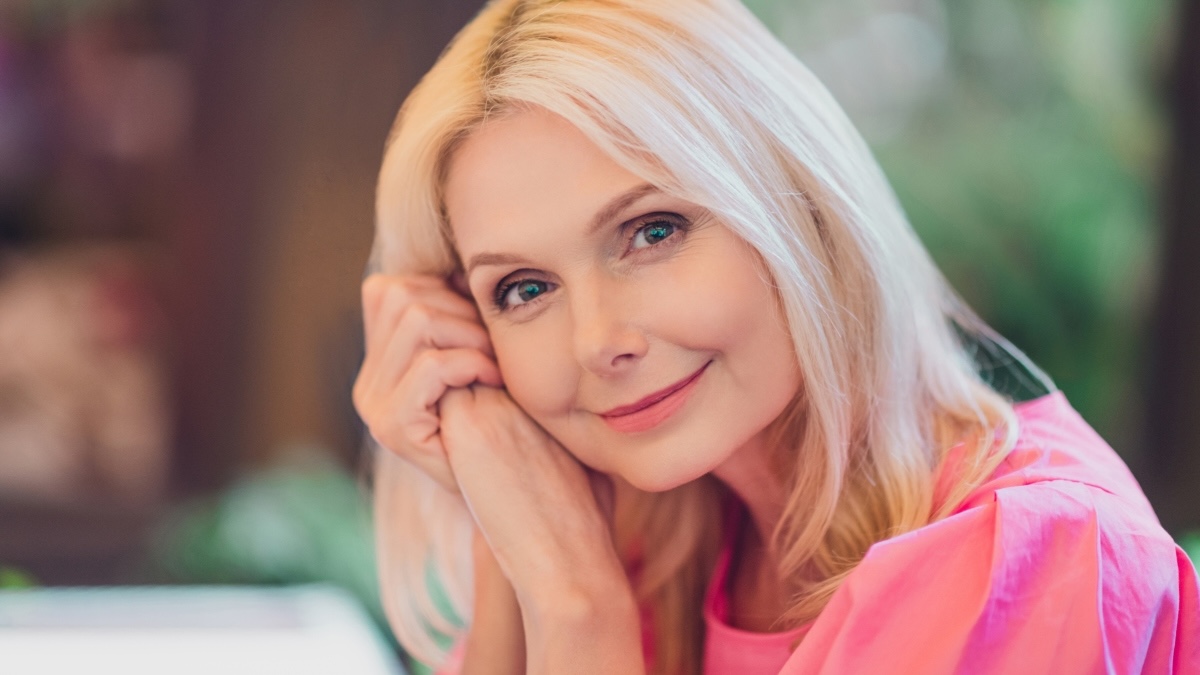 A woman in pink smiling after learning how to talk to her doctor