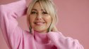 A woman in pink with low desire smiling while running her hands through her hair