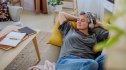 A woman listening to relaxing music on a couch wearing headphones