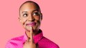 A woman against a pink background with her hand on her chin thinking about the gap in sexual health research
