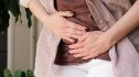 Close-up of a woman holding her stomach in pain, an early sign of colon cancer