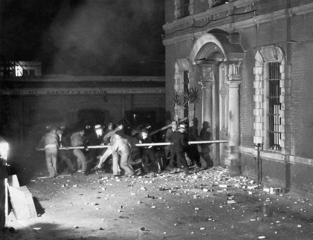 The lynch mob using 30 foot long pieces of pipe to break down the iron doors of the county jail to get to Thomas Thurmond and John Holmes, the kidnapers and slayers of Brooke Hart, San Jose, California, November 27, 1933. 
