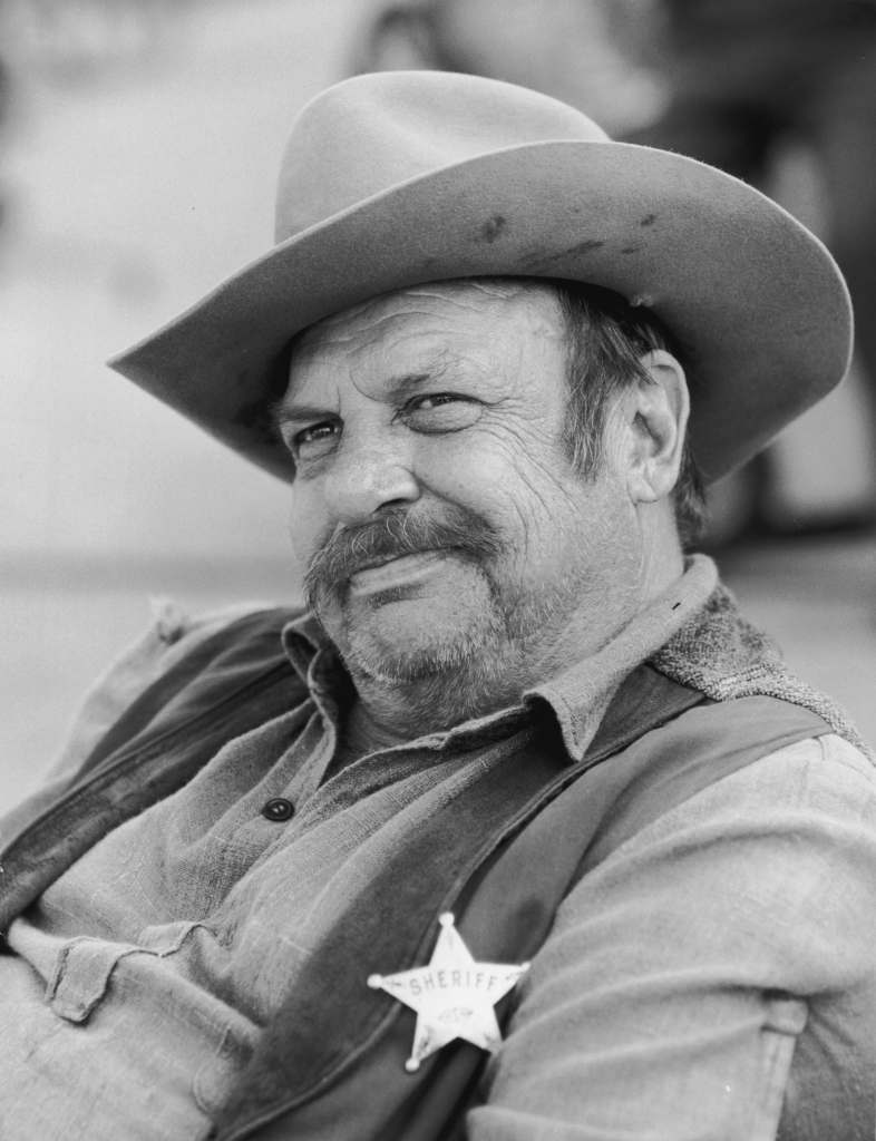 Jackie Coogan (1914-1984), sitting and wearing a sheriff's badge and a cowboy hat, from the television program, 'Dirty Sally'. 