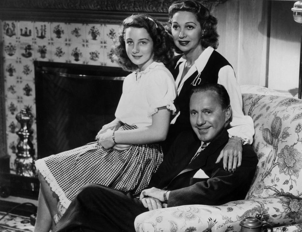 circa 1945: Family portrait of American comedian Jack Benny, his wife, Mary Livingstone, and their teenage daughter Joan Benny, seated together in a living room.