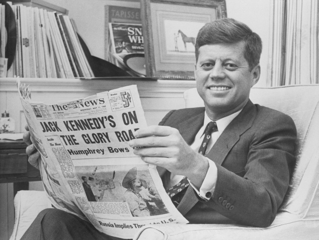(Original Caption) Senator John F. Kennedy relaxes in his home today holding a newspaper reporting his smashing victory over Senator Humphrey in the West Virginia Primary.