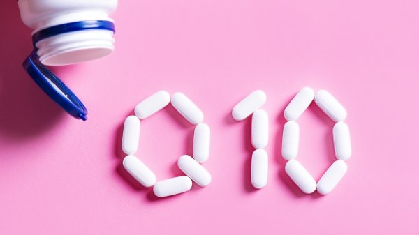 White pills arranged to spell Q10 (for CoQ10) against a pink background