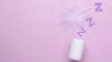 A white bottle of magnesium pillows with purple Zzzs coming out of it to represent sleep against a purple background