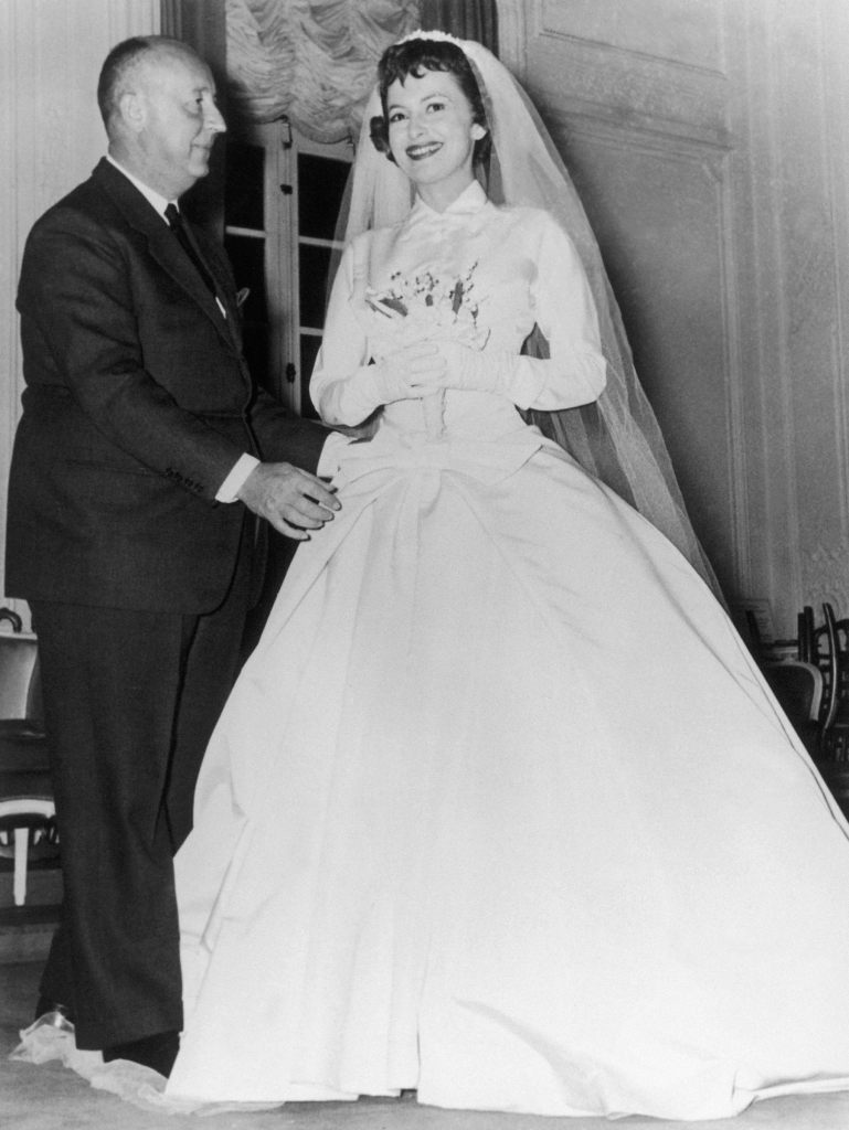 FRANCE - OCTOBER 20: 10/20/1955. The American Actress Olivia De Havilland Wearing A Christian Dior Wedding Dress For The Film La Fille De L'Ambassadeur. The Fashion Designer Is Making The Last Alterations. (Photo by Keystone-France/Gamma-Keystone via Getty Images)