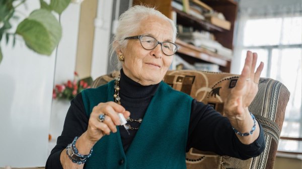 Older woman giving herself a manicure to smooth the ridges in her nails