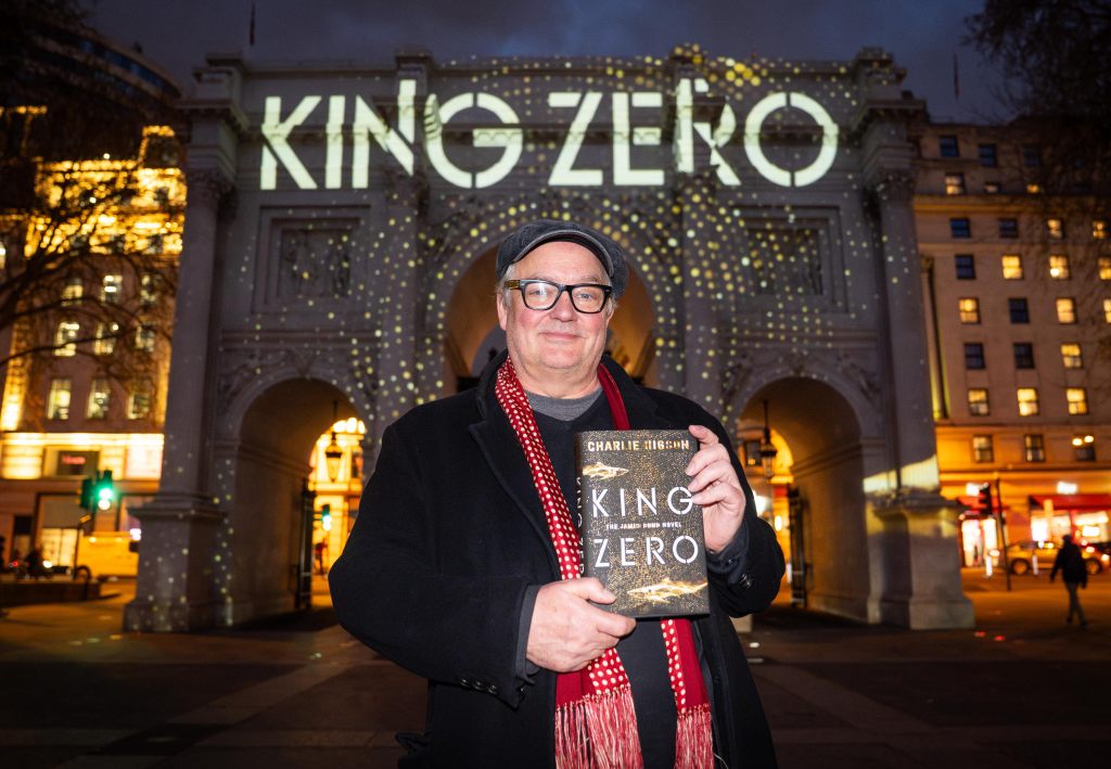 Charlie Higson poses in front of a projection at Marble Arch, London, launching his new James Bond novel, King Zero, the first publication of a James Bond novel for adults from a new author in 10 years. Picture date: Tuesday March 31, 2026.