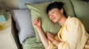A woman sleeping peacefully in her bed after leaning how to prevent night sweats
