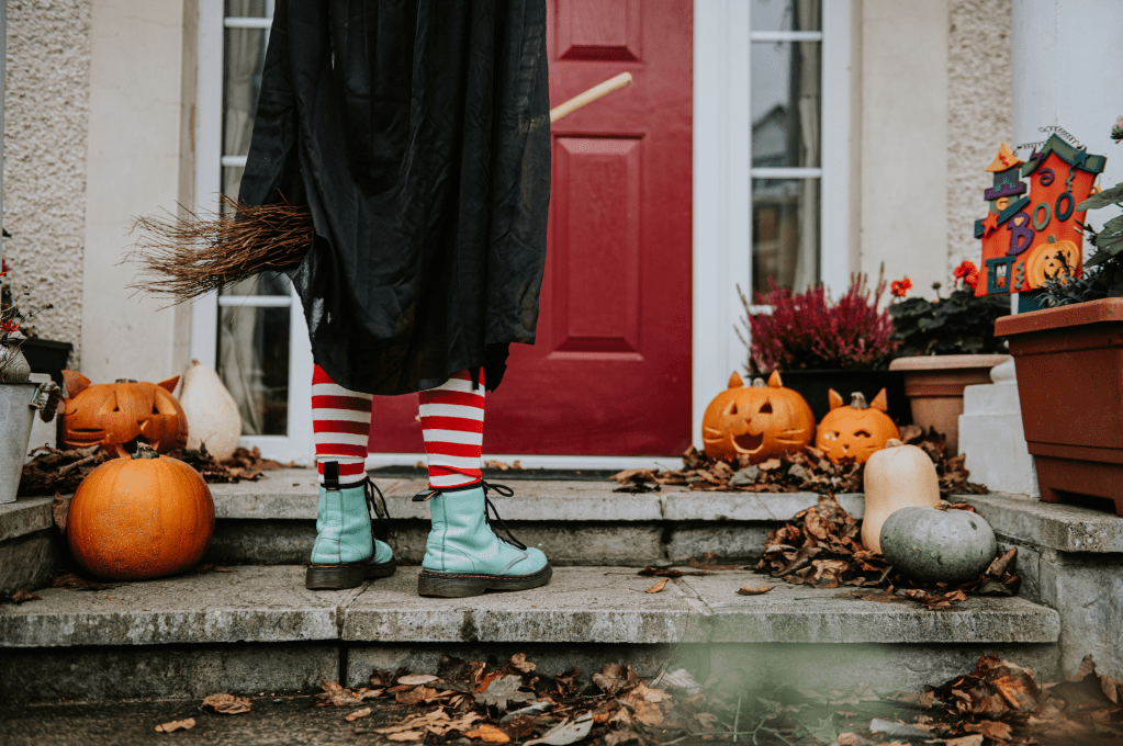 Porch decorated for Halloween with a trick-or-treater on it