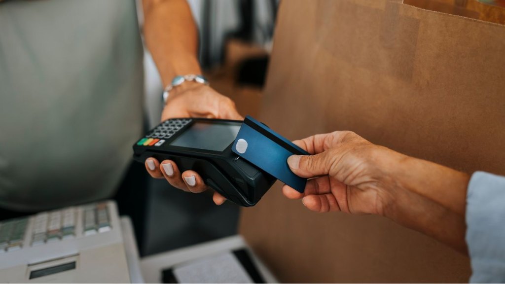 Over the shoulder view of a contactless payment using a smartphone and credit card at a market