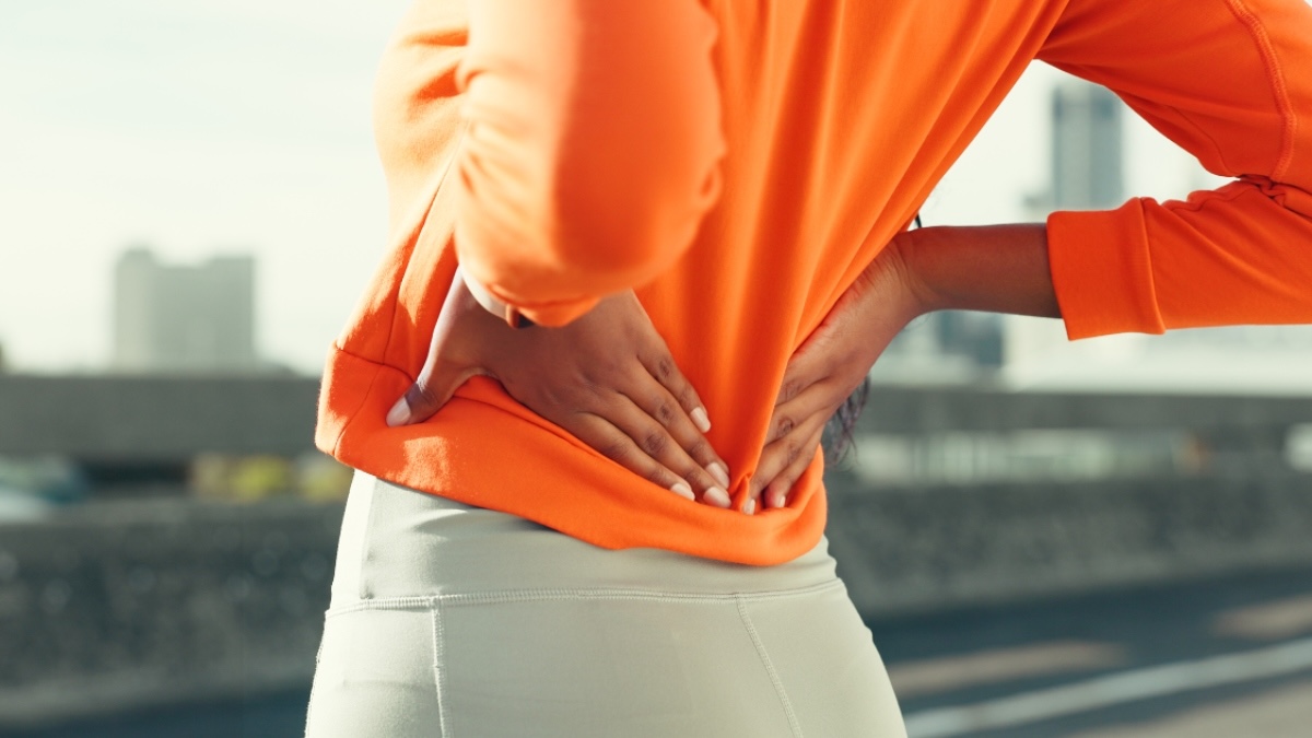Close-up of a woman's hands on her back as she experiences back pain